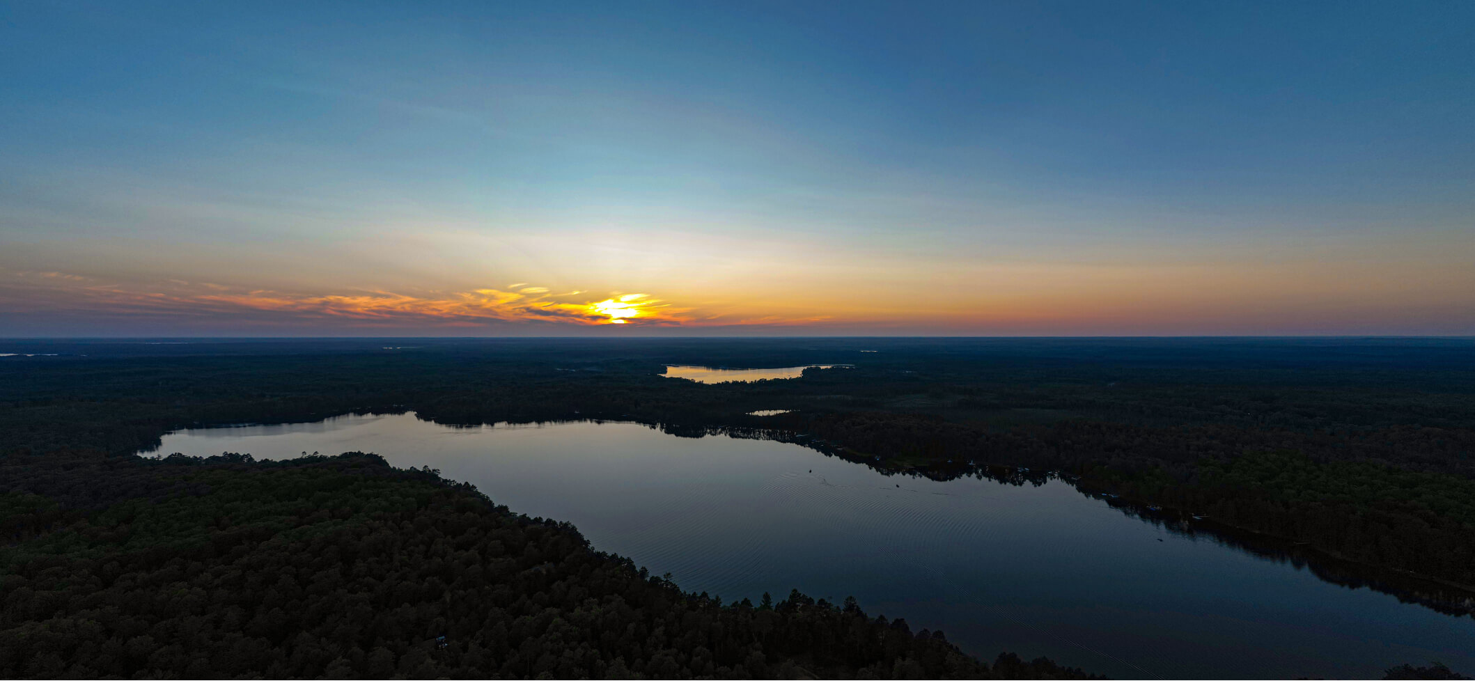 Sunset over a quiet lake surrounded by forest